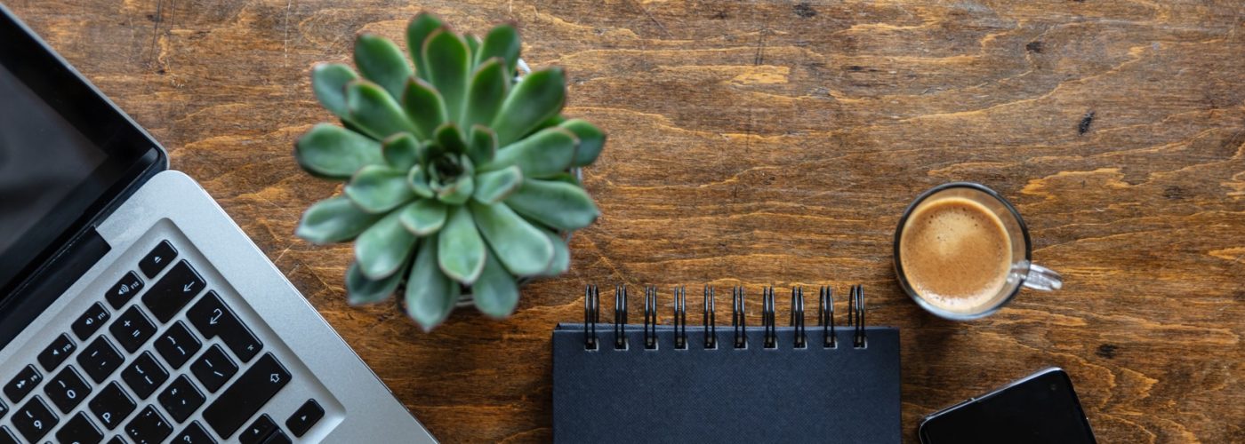 Office desk, cozy warm workspace. Computer laptop and mobile phone on a chestnut wood table, top view, copy space